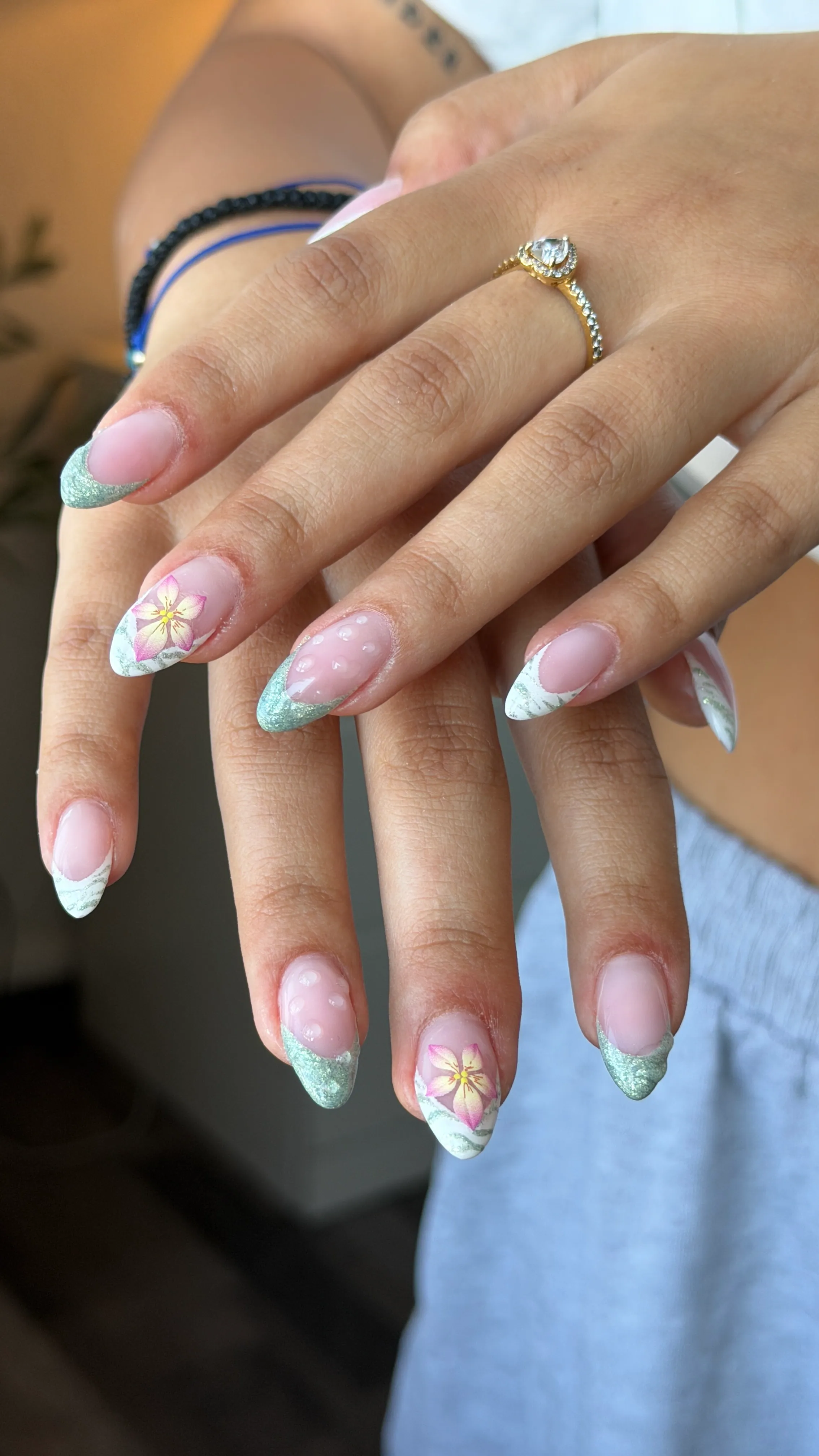 Nude Nägel mit pastellgrünen Spitzen und kleinen gemalten Blumen