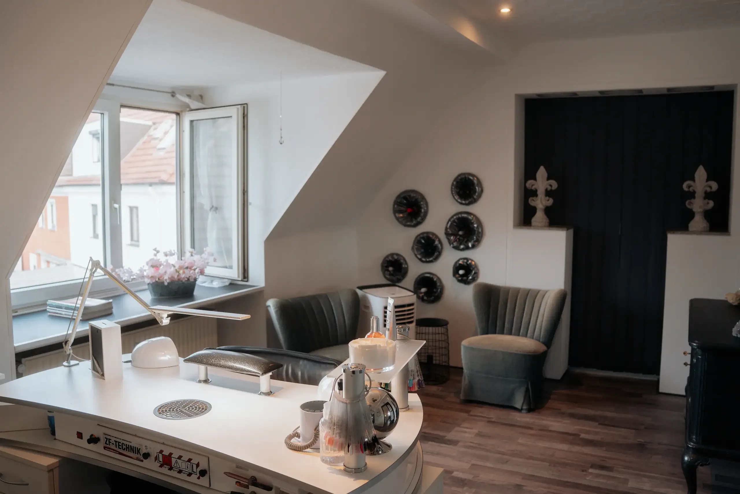 Das Nagelstudio unter der Dachschräge mit geschwungenem Arbeitstisch und Sesseln
