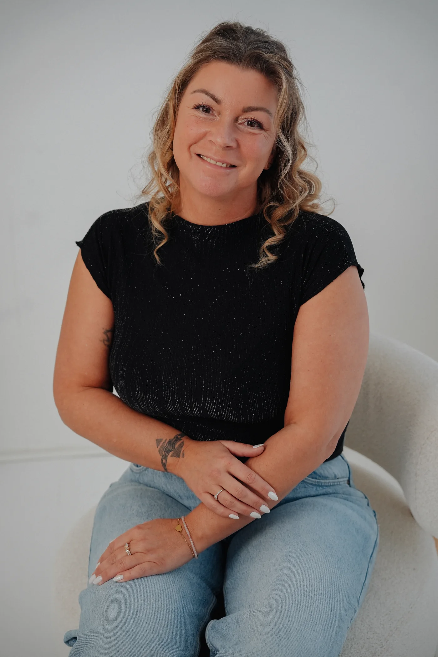 Porträt von Diana Lachmuth, lächelnd, auf einem hellen Sessel sitzend